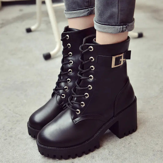 Black leather boots with a buckle on a neutral background